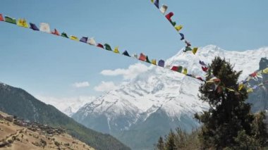 Rüzgarda dalgalanan bayraklar, Nepal 'in Ghyaru köyünün yakınındaki Annapurna' ya kar yağıyor.