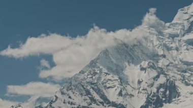 Nepal 'deki Annapurna Dağı' nın devasa kar sırtı üzerinde beyaz bulutlar sürünüyor.