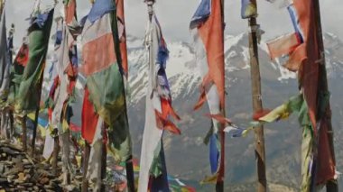 Sert kar dağının üzerinde dalgalanan bayrak direkleri üzerinde renkli Budist dua bayrağı, Nepal