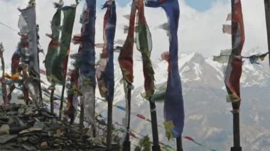 Şiddetli kar dağlarına karşı direkler üzerinde renkli dua bayrakları dalgalanıyor, Nepal