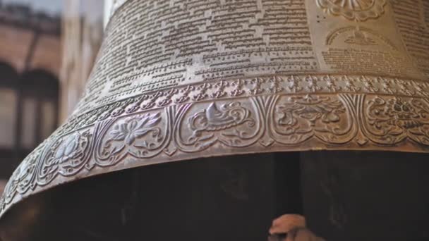 Massive metal bell hanging near Boudhanath, ornate carving exterior, writings — Stock Video