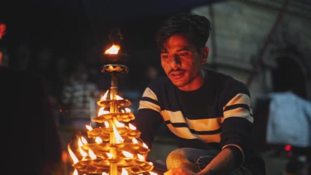 KATHMANDU, NEPAL - CIRCA, 2019: Индуистский преданный сидит возле больших свечей — стоковое видео