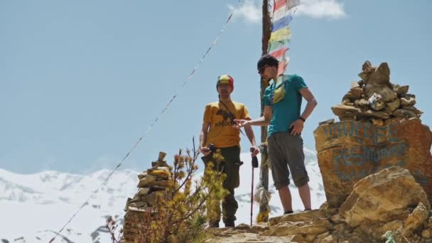 GHYARU, NEPAL - CIRCA, 2019: Молодые люди стоят на смотровой площадке рядом со снежной горой — стоковое видео