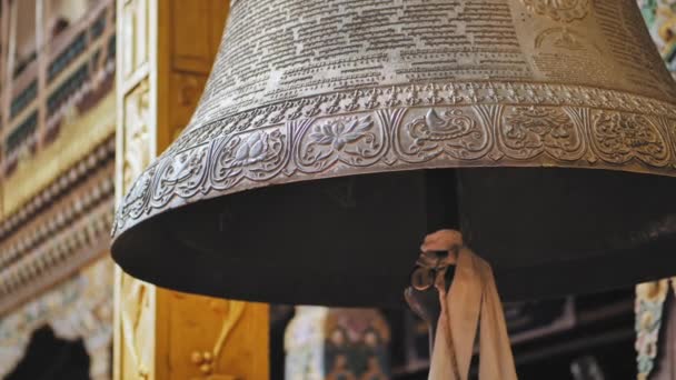 El hombre borroso camina ante la gran campana adornada que cuelga cerca de Boudhanath, detalles del ornamento — Vídeo de stock