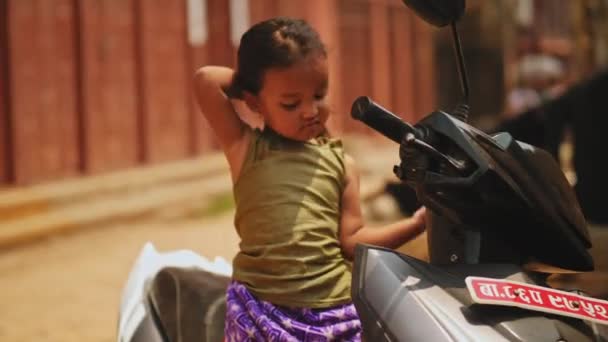 Kathmandu, Nepál - Circa, 2019: Malá hezká nepálská holčička sedící na skútru — Stock video