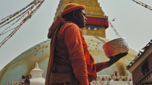 Kathmandu, Nepál - Circa, 2019: Narancssárga ruhás férfi áll a Boudhanath sztúpánál — Stock videók