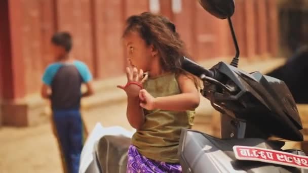 Kathmandu, Nepal - Circa, 2019: Kleine nepalese girly zittend op motor — Stockvideo