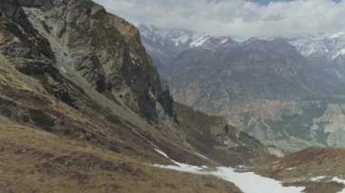 Uçuşlar dağlık kayalıkların üzerinden geniş vadideki bulutlu kar dağlarına doğru.