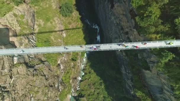 Turisták átkelés keskeny felfüggesztés híd felett mély folyó szurdok — Stock videók