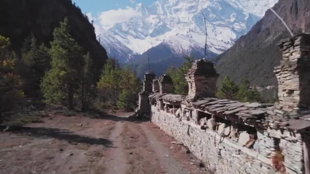 Trekking weg in de buurt van Mani muur leiden door bos naar besneeuwde Annapurna Ii berg — Stockvideo