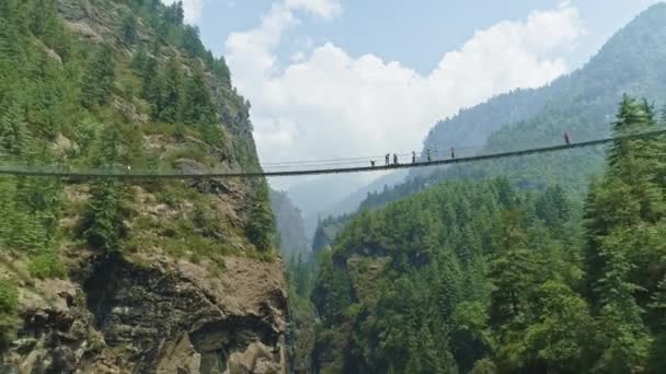 Panorama, cestovatelé přes visutý most nad hlubokou horskou soutěskou, Nepál — Stock video