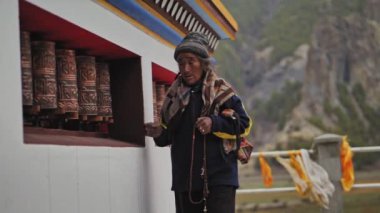 Manang, Nepal - 2019 yılı dolaylarında Mala 'da dua tekerlekleri dönen yaşlı nepalli kadın