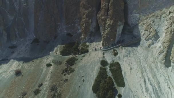 Туристы ходят по опасной тропинке по склону над острыми крутыми скалами — стоковое видео