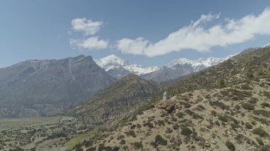 Gökyüzü panoramiası, geniş güneşli dağ vadisi karlı kayalık tepelerin eteklerinde.
