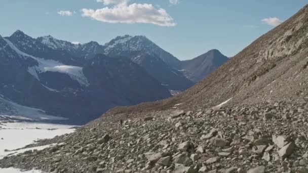 Vuelo aéreo, los turistas suben por una enorme pendiente en la morrena nevada — Vídeo de stock