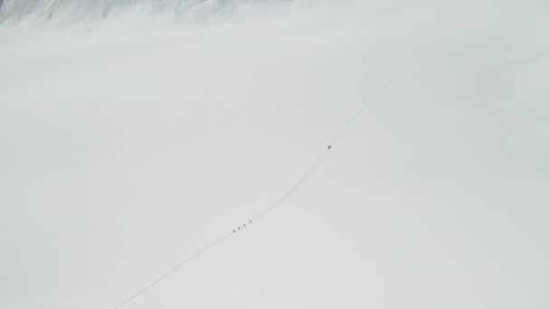 Панорама очей птахів, альпіністи рухаються на широкому сніговому полі, піднімаючись на вершину гори — стокове відео