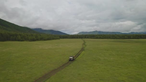 Panorama, bulutlarla kaplı orman tepelerinin etrafındaki yeşil vadide bir kamyonla seyahat et. — Stok video