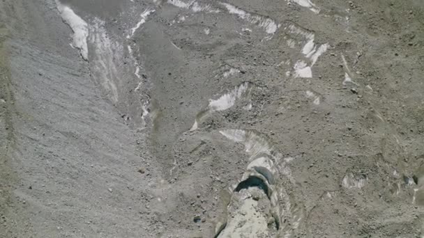 Aerea volare sopra la morena rocciosa, sciogliere corsi d'acqua scorre da sotto il ghiacciaio — Video Stock