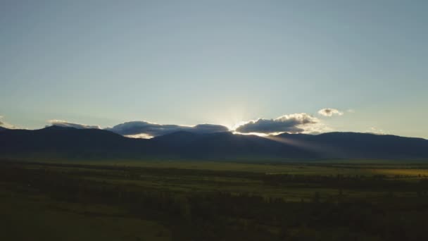 Сказочная панорама восхода солнца, солнечные лучи вокруг светящегося облака, золотой свет на темной долине — стоковое видео