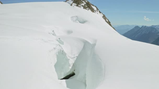 Nieve densa de las tierras altas, colapso peligroso, grieta de nieve en el borde de la pendiente de la montaña — Vídeos de Stock