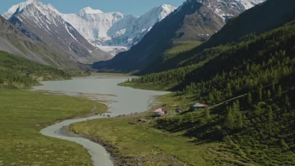 Los jinetes cruzan el río lechoso cerca de la base turística en los pies de montaña del bosque — Vídeo de stock