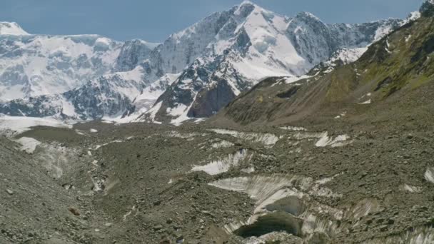 Havas hegyi tornyok felett gleccser nyelv, olvadt víz folyik át sziklás folyómeder — Stock videók