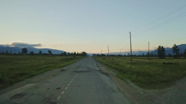 Soumrak, ptačí oko panorama, prázdná cesta uprostřed prostorného zeleného údolí — Stock video