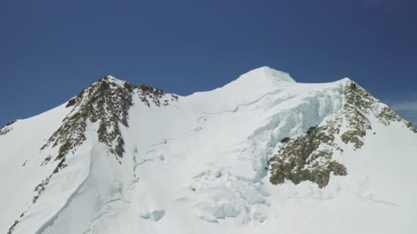 Высотная панорама, ослепительная вершина снежной горы, возвышающаяся на ясном голубом небе — стоковое видео