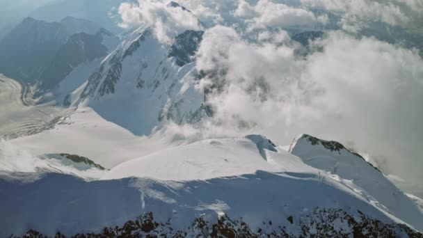 Impresionante vista de aves, escaladores en la cima de la montaña de nieve, grandes nubes alrededor de la cumbre — Vídeo de stock
