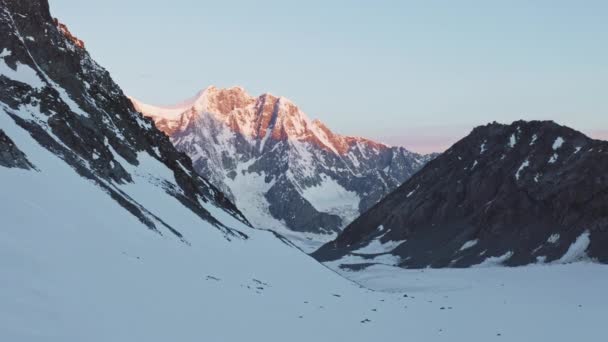Panorama aéreo, gama de montanhas de neve escura em luz rosa do amanhecer da manhã — Vídeo de Stock