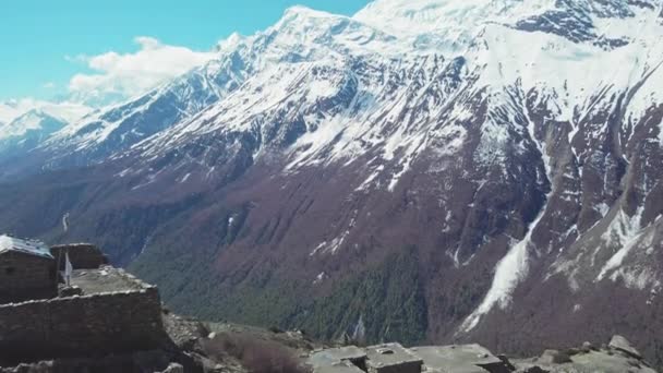 Дрон летить над кам'яними руїнами втраченого високогірного села поблизу гігантської сніжної гори — стокове відео