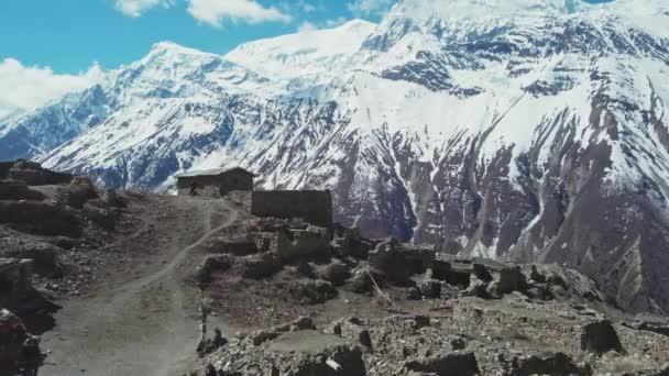 Turisti a piedi in rovine di pietra del villaggio altopiano perso vicino montagna di neve gigante — Video Stock