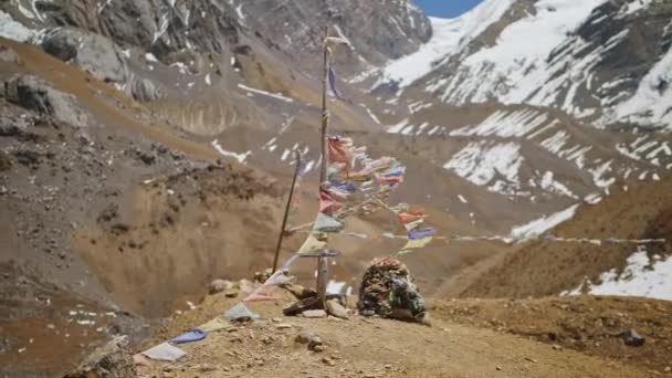 Sten med trasiga böneflaggor står på bergskanten, landmärke vid snöhöglandet — Stockvideo
