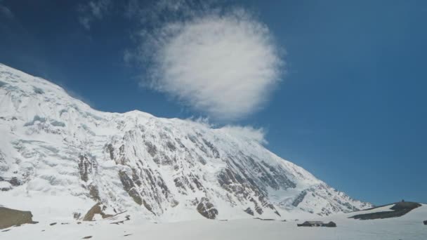 Impressionante nuvem redonda pairar no céu azul ensolarado acima do pico da montanha nevada, panorama — Vídeo de Stock