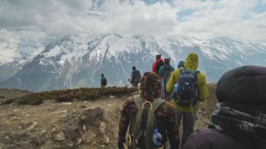 Turist seferi dağlarda dev bir kar yığınının yanında bulutların içinde ilerliyor.