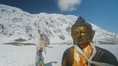 Bouddha 'nın bronz heykeli kar altında parlıyor. Mavi gökyüzündeki bulutlara karşı.