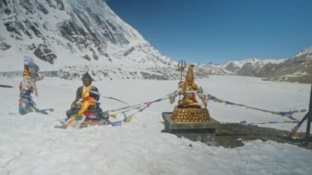 Staty av Bouddha och Shiva skiner i snö höglandet mot klarblå himmel — Stockvideo