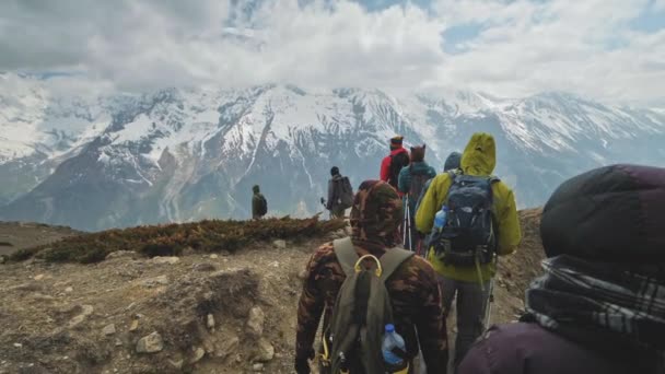 Turistická výprava dolů v horách vedle obřího sněhového masivu v oblacích — Stock video