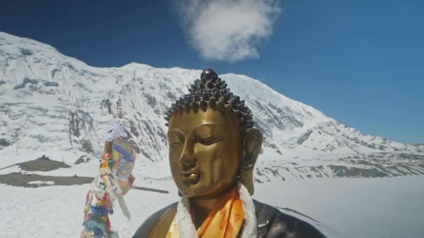 Bronzen beeld van Bouddha stralend in sneeuw hooglanden tegen wolk in blauwe lucht — Stockvideo