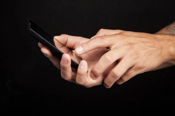 Hombre con teléfono celular en las manos sobre fondo negro — Foto de Stock