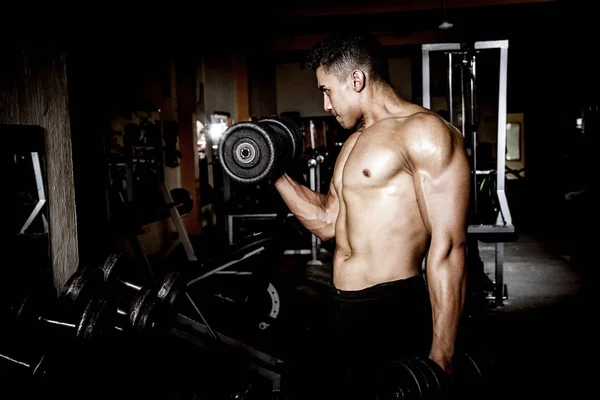 Young man exercising in dark and old gym — Stock Photo, Image