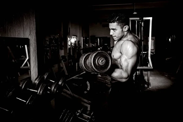 Giovane uomo che esercita in palestra scuro e vecchio — Foto Stock