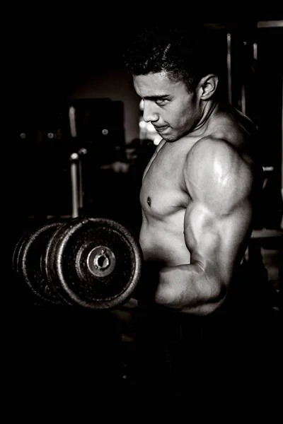 Giovane uomo che esercita in palestra scuro e vecchio — Foto Stock