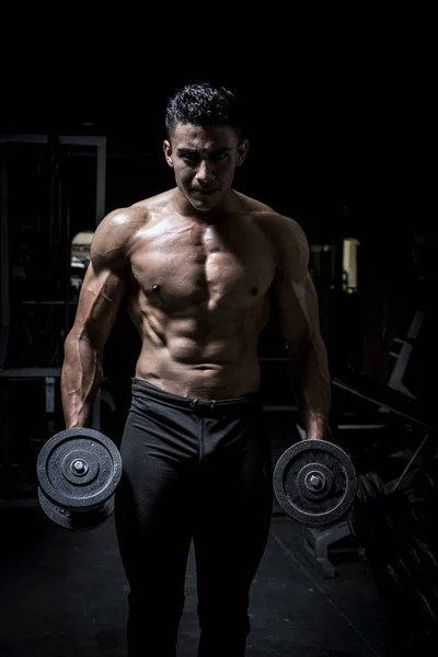 Young man exercising in dark and old gym — Stock Photo, Image