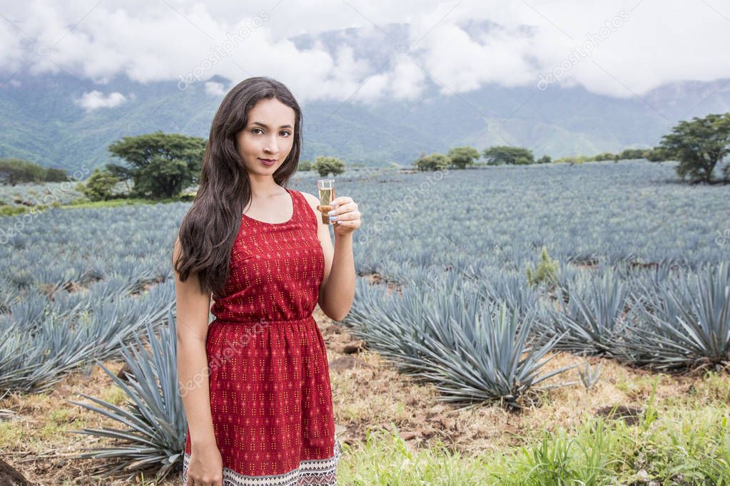 Mexican woman with tequila shot in a landscape of Tequila.