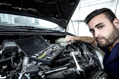 Garajdaki tamirci motoru tamir ediyor.