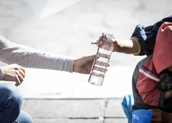 La mano de una mujer dando algo a un indigente — Foto de Stock