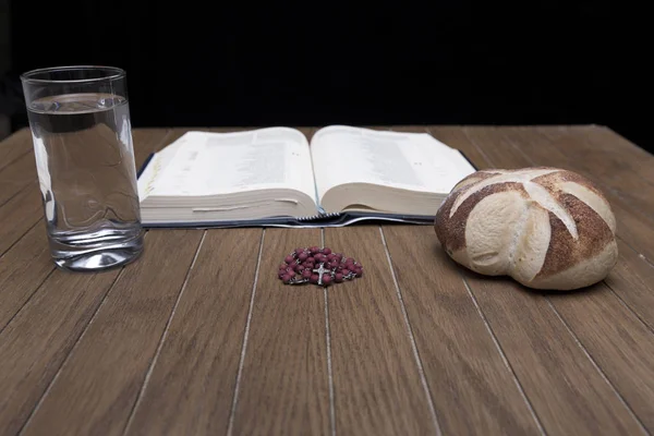 Artisan breads and water glasses on wooden table in dark room — Stock Photo, Image