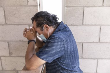 Dua kilisesinde virüs salgını sırasında maskeli bir adam dua ediyordu. Kutsal Üçlü. İlahi Takdir.