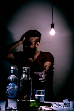 Sakallı genç adam, alkolizm, sigara ve uyuşturucu bağımlılığında kaybolmuş.